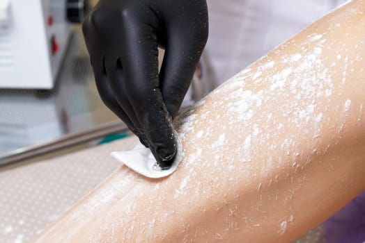 Beautician getting ready to wax female legs in spa center