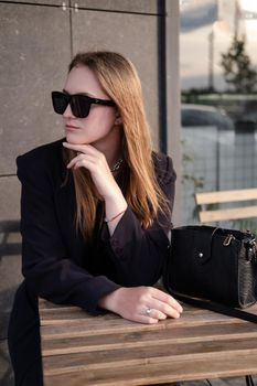 pretty brunette woman sitting by wooden table outside. feminine. millennial people. lady on coffee break.