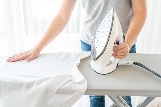 Close up of Female hands ironing white shirt on ironing board