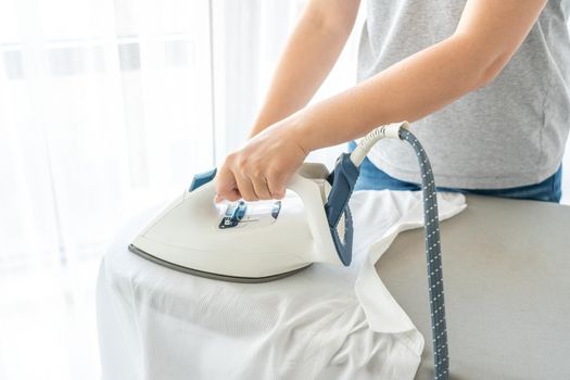 Close up of Female hands ironing white shirt on ironing board