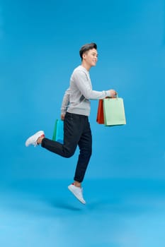 Full size photo of crazy handsome guy hurry rush hold packages jump isolated on blue color background