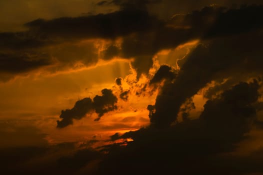 Evening sunrise in the storm clouds of a dramatic sky. The sun behind a dark cloud. Evening sky. Climatic conditions. Weather forecast. Background image.