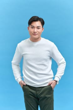 charming cheerful positive young man hold hands pockets isolated on blue background
