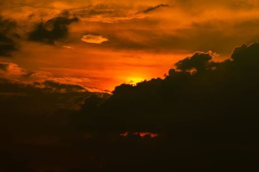 Evening sunrise in the storm clouds of a dramatic sky. The sun behind a dark cloud. Evening sky. Climatic conditions. Weather forecast. Background image.