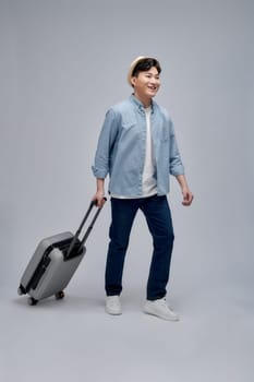 Traveler asian man standing with suitcase isolated over white background