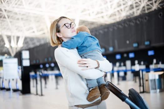 Motherat happily holding and lifting his infant baby boy child in the air after being rejunited in front of airport terminal station. Baby travel concept