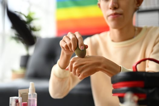 Young male makeup artist applying liquid foundation on hand, testing cosmetics skin tone texture.