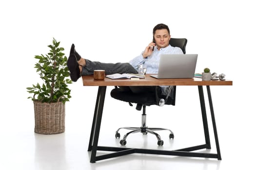 Successful happy businessman working with laptop and having phone conversation with client