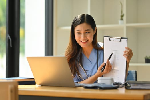 Smiling female doctor having online consultation with patient on laptop in clinic. Tele medical, healthcare and technology.