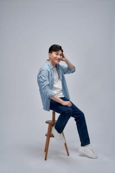 Handsome man sitting on stool against white background