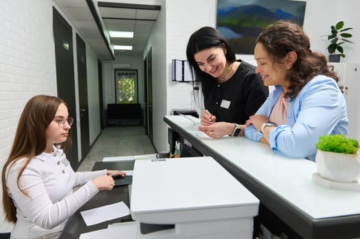 Portrait of a female dental hygienist, doctor dentist, patient and manager talking at reception counter in dentistry clinic. Happy client at dentist appointment. People. Healthcare and medicine.