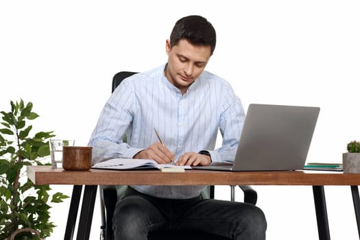 businessman in blue shirt taking notes, using laptop computer on white background