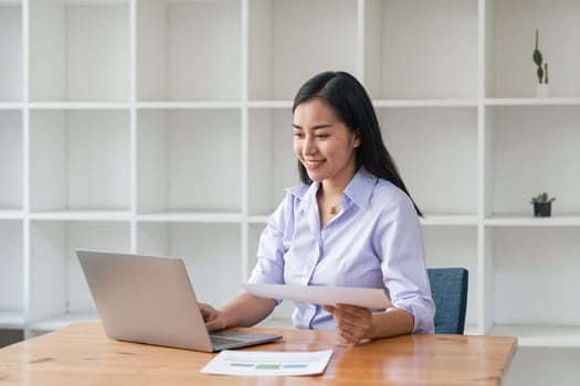 Asian businesswoman working for financial graphs showing results about their investments, planning successful business growth process by laptop computer.