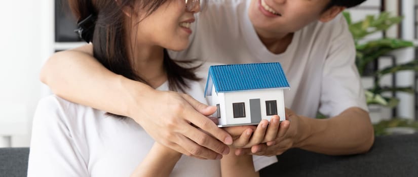 Young loving couple with small wooden house new home concept.