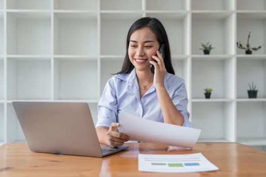 Asian businesswoman working for financial graphs showing results about their investments, planning successful business growth process by laptop computer.