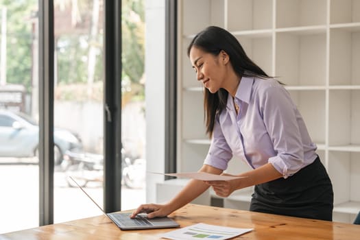 Asian businesswoman working for financial graphs showing results about their investments, planning successful business growth process by laptop computer.