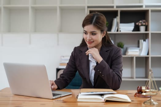 Attractive young lawyer in office Business woman and lawyers with brass scale on wooden desk in office. Law, legal services, advice, Justice and real estate concept.