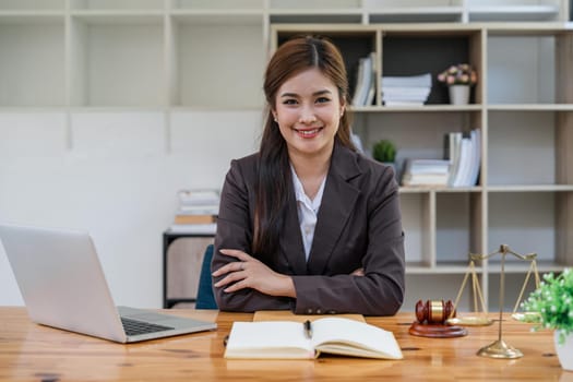 Attractive young lawyer in office Business woman and lawyers with brass scale on wooden desk in office. Law, legal services, advice, Justice and real estate concept.