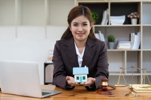 Happy smiling lawyer manager holding house model. possibly real estate, lawyer. non-profit, marketing.