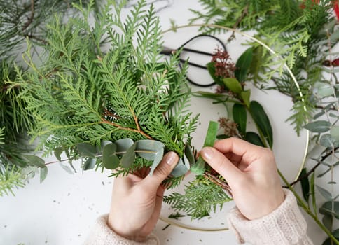 The process of making a Christmas wreath from needles, thuja, shimia, rosehip, pine twigs, chopped twigs for the wreath. The concept of preparation for Christmas and New Year