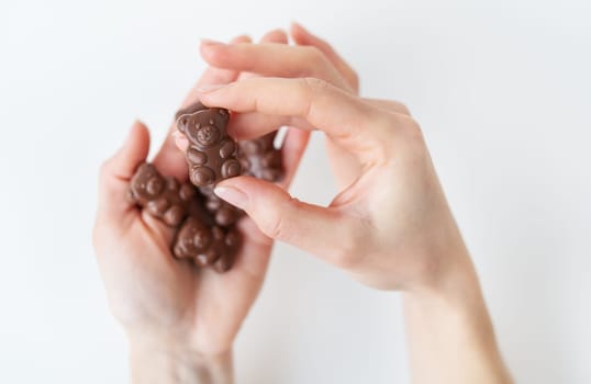 The girl holds a chocolate teddy bear in her hands on a white background. Charming chocolate and delicious gift