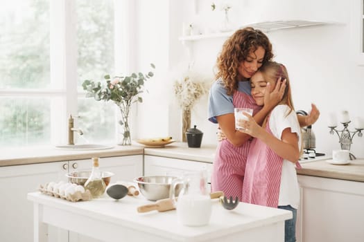 Portrait of a teen girl with her mother at home in kitchen, close up