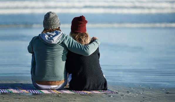 Let the beauty of nature bring you together. Rearview shot of a young couple sitting on the beach