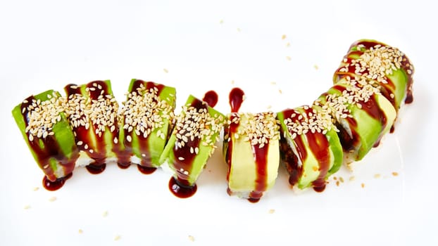 uramaki sushi roll with smoked eel unagi covered by avocado and sesame seeds on white background.