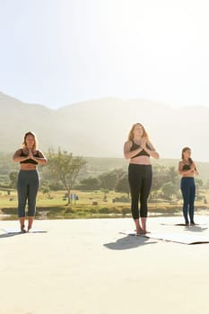 The health benefits of yoga are very real. three young women practicing yoga on the beach