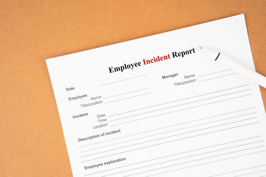 Employee incident report form document and and pen on blue background.