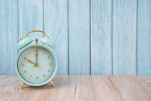 Vintage retro alarm clock ten time 10 o'clock on table wood with dark background.