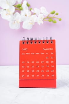 Red calendar September 2023. Desk calendar for year 2023 and white orchid.