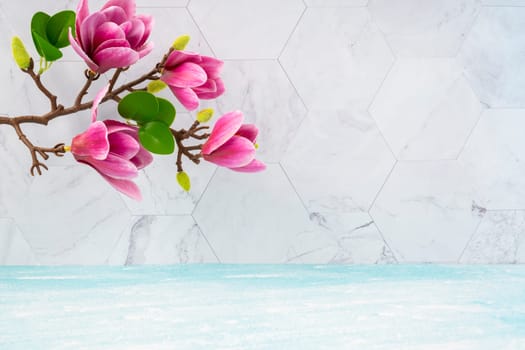 Beautiful pink magnolia flowers on blue wooden floor and marble background with copy space for your design.