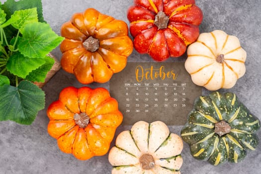 October 2023 Calendar and pumpkins on black wood background.
