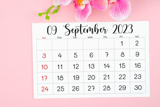 September 2023 calendar page and pink orchid on pink background.