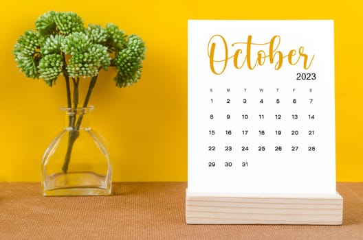 October 2023 Monthly desk calendar for 2023 year with flower pot on yellow background.