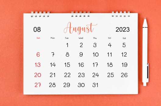 August 2023 Monthly desk calendar for 2023 year and pen on red background.