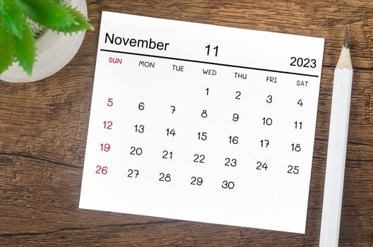 November 2023 Monthly calendar for 2023 year with pen on wooden background.