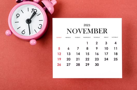 November 2023 Monthly calendar year with alarm clock on red and black background.