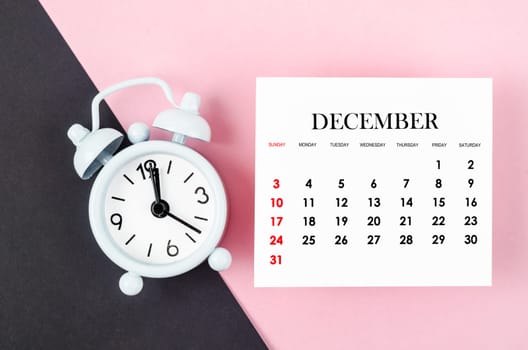December 2023 Monthly calendar year with alarm clock on pink and black background.