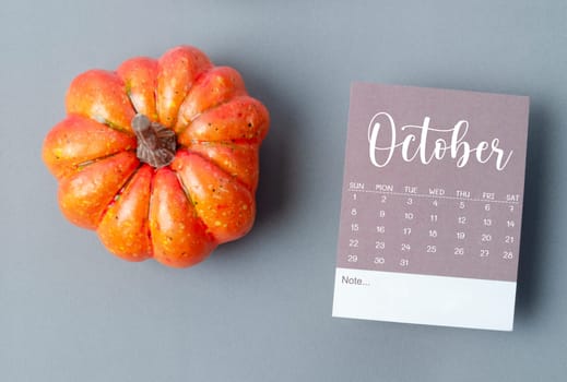 October 2023 Calendar and pumpkins on gray color cardboard background.