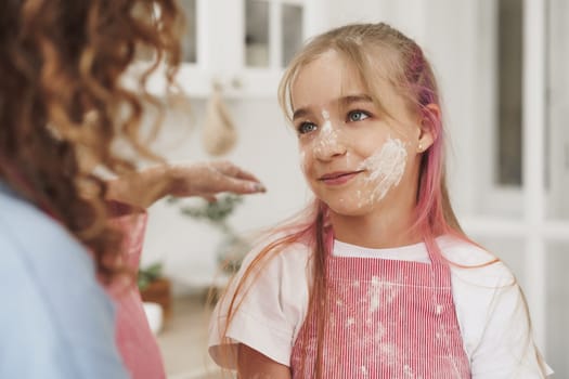 Mother and daughter having fun while cooking dough in kitchen, close up