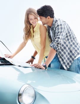 Taking the romantic route. A cute young couple checking over a map together while on a road trip