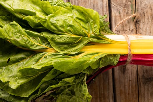 Overhead close-up of spinach bundle on wooden table. unaltered, leaf vegetable, healthy food, raw food and organic concept.