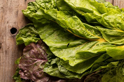 Directly above close-up shot of fresh leaf vegetable on wooden table. unaltered, leaf vegetable, healthy food, raw food and organic concept.