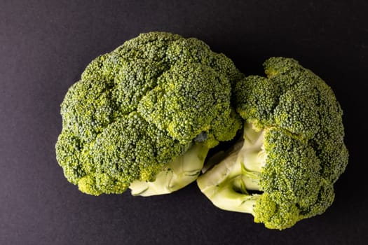 Overhead close-up of broccolis on black background. unaltered, vegetable, healthy food, raw food and organic concept.