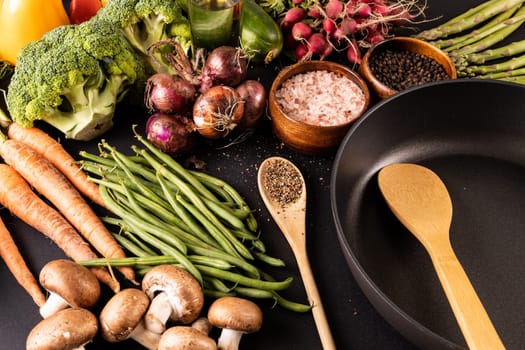 Frying pan with spices and various vegetables and oil bottle on table. unaltered, vegetable, healthy food, raw food, variation and organic concept.