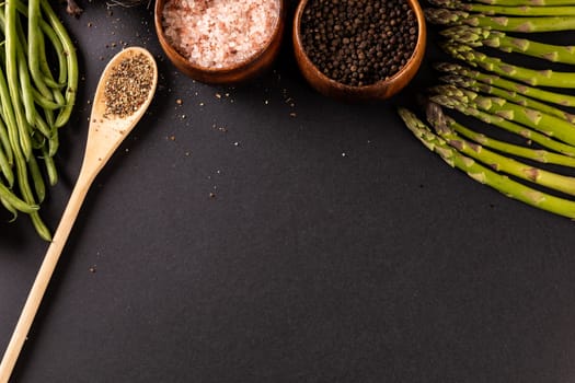 High angle view of spices with asparagus and french beans on black background with copy space. unaltered, vegetable, healthy food, raw food, variation and organic concept.