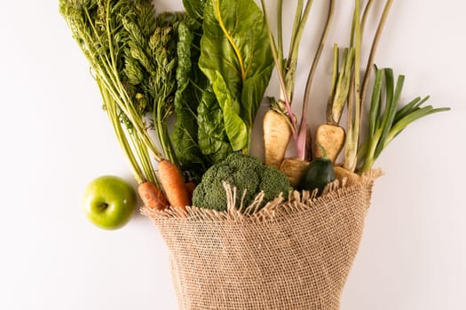 Overhead view of fresh vegetables with burlap on white background, copy space. unaltered, food, healthy eating, organic.