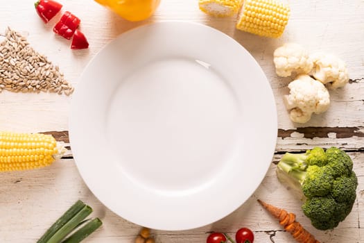 Directly above shot of ingredients arranged around white empty plate on table, copy space. unaltered, food, preparation, healthy eating.